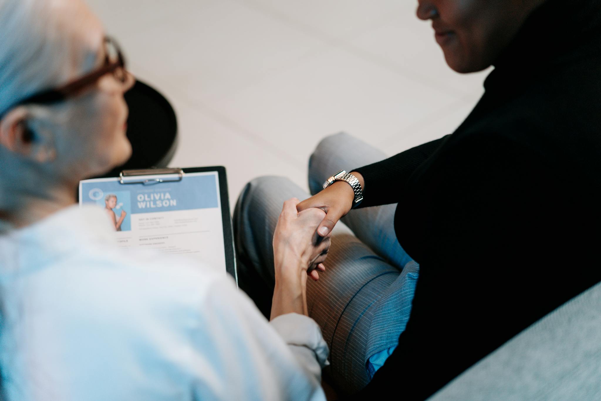 Two professional women having a handshake in an office setting, focusing on recruitment and connection.
